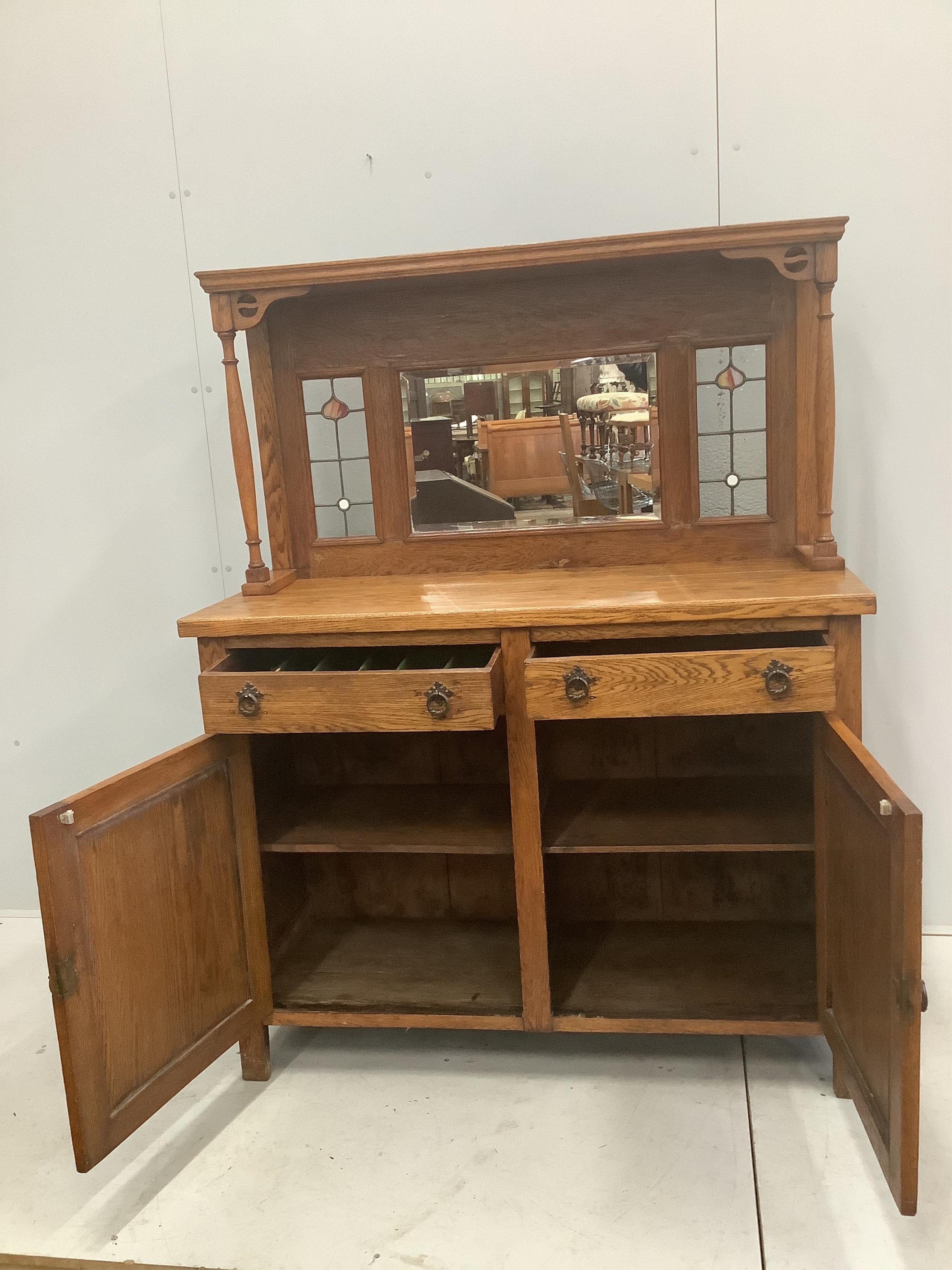 An Arts and Crafts oak sideboard, with stained glass raised mirrored back, width 122cm, depth 48cm, height 155cm. Condition - fair